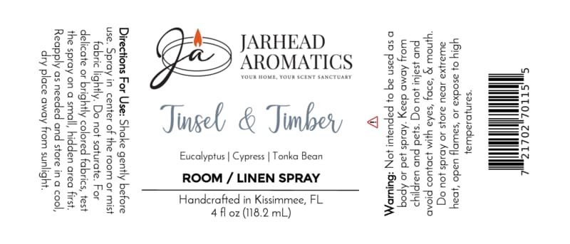 Label for a Jarhead Aromatics Tinsel & Timber Room & Linen Spray bottle, detailing a winter forest scent of eucalyptus, pine, smoke, and tonka bean, with usage directions, safety warnings, and a barcode.