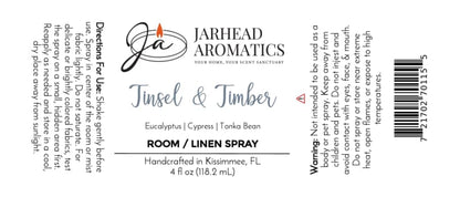 Label for a Jarhead Aromatics Tinsel & Timber Room & Linen Spray bottle, detailing a winter forest scent of eucalyptus, pine, smoke, and tonka bean, with usage directions, safety warnings, and a barcode.