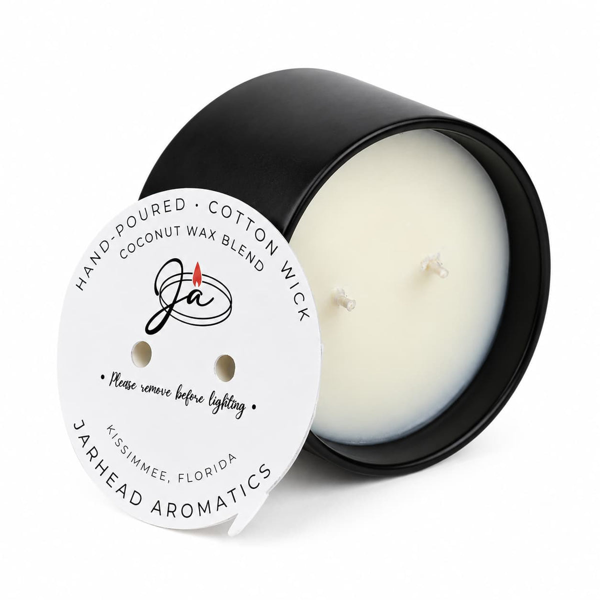A two-wick black Coconut Wax Blend Candle, topped with a circular paper label reading hand-poured coconut wax blend and safety instructions to remove before lighting.
