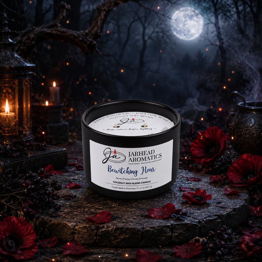 A black Bewitching Hour Coconut Wax Blend Candle sits on a stone surface surrounded by dark red poppy flowers, with a misty forest and full moon in the background.