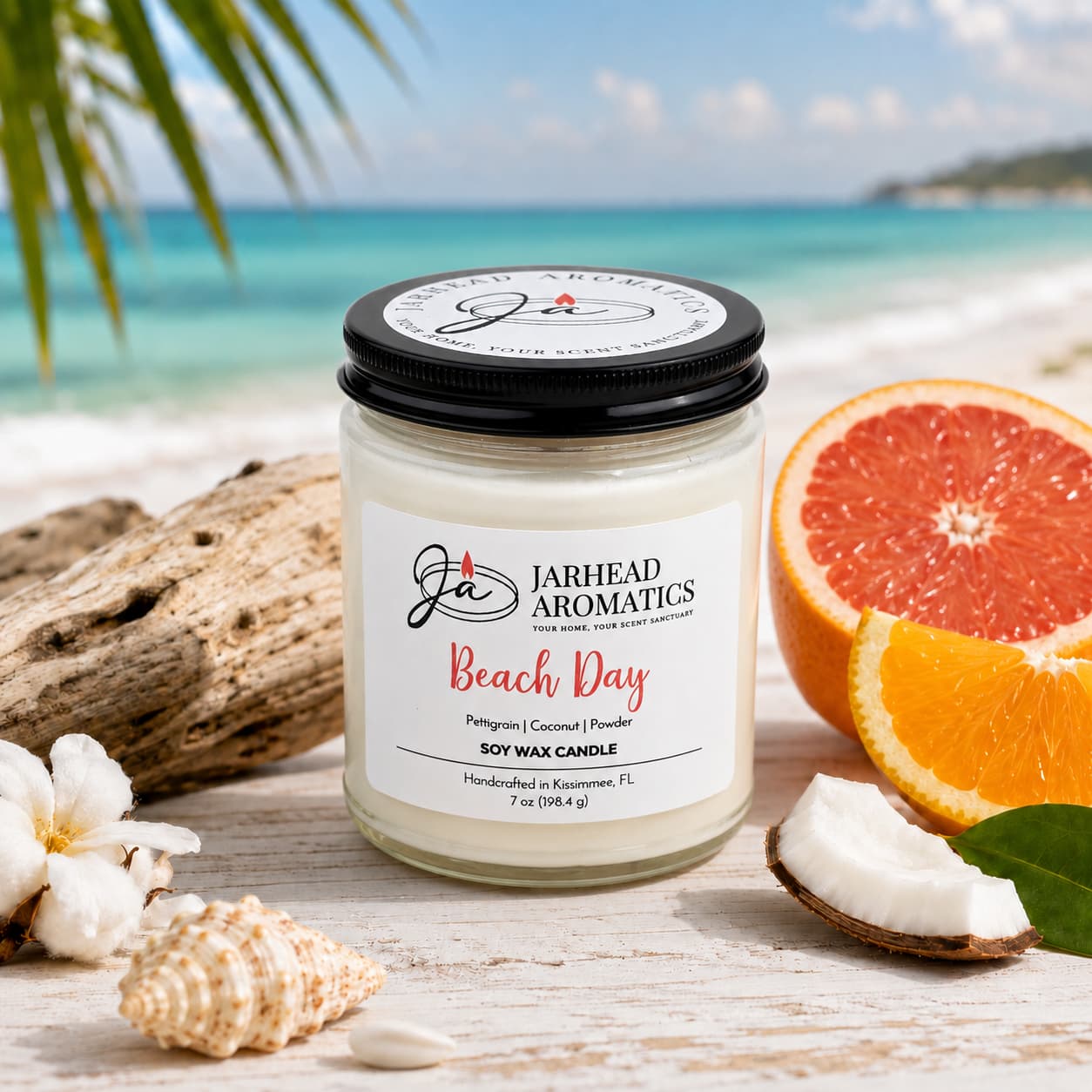 A Beach Day Soy Wax Candle by Jarhead Aromatics rests on sand among seashells, coconut, cotton, and slices of grapefruit and orange, with a tropical ocean and palm leaves in the background. The Coconut, Citrus & Coastal Breeze Candle fills your space with a long-lasting coastal fragrance that perfectly embodies the relaxing essence of a day by the shore.