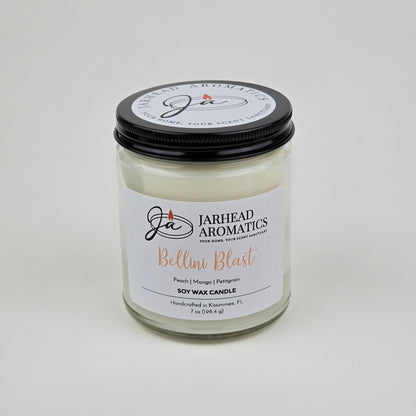 The Bellini Blast Soy Wax Candle by Jarhead Aromatics features peach, mango, and tangerine scents. This handcrafted glass jar candle has a black lid, white label, and is made in Kissimmee, FL.