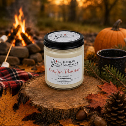 A Jarhead Aromatics Campfire Memories Soy Wax Candle—featuring notes of smoky embers, maple, moss, and patchouli—rests on a tree stump surrounded by autumn leaves, pinecones, a pumpkin, and a mug, with marshmallows roasting by the campfire in the background. This fall candle perfectly captures the warmth and nostalgia of autumn nights.
