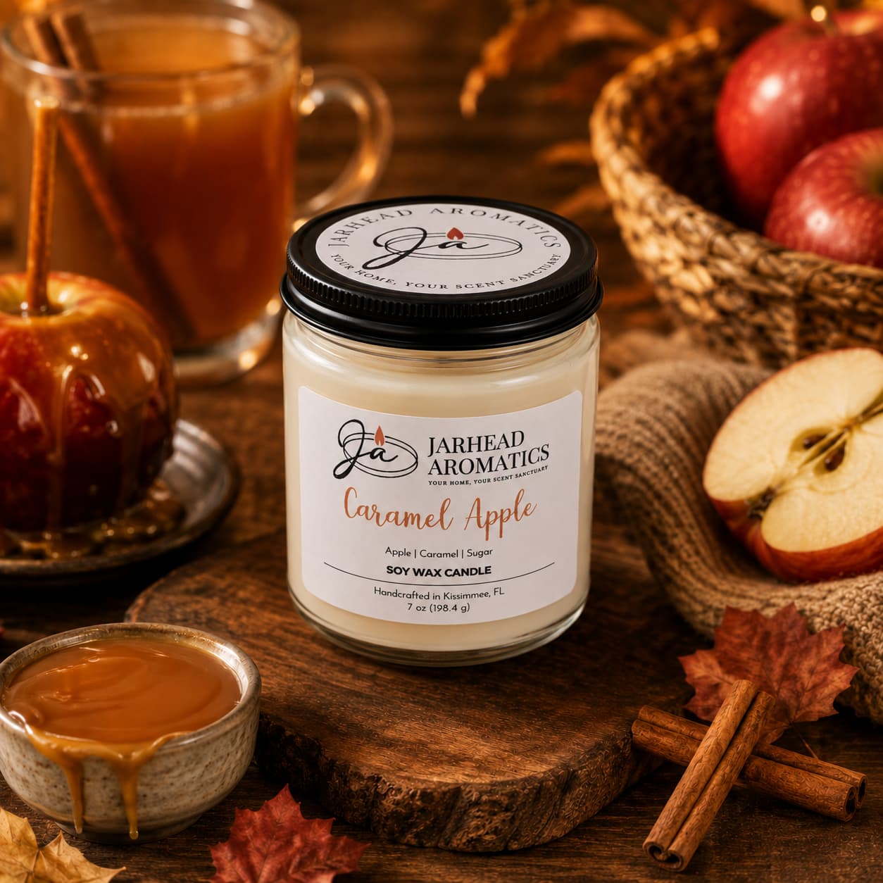 A Jarhead Aromatics Caramel Apple Soy Wax Candle | Apple Cider, Caramel & Sugar Candle rests on a wooden table surrounded by apples, a caramel apple, cinnamon sticks, caramel sauce, and a mug of apple cider, creating a warm and cozy autumn ambiance.