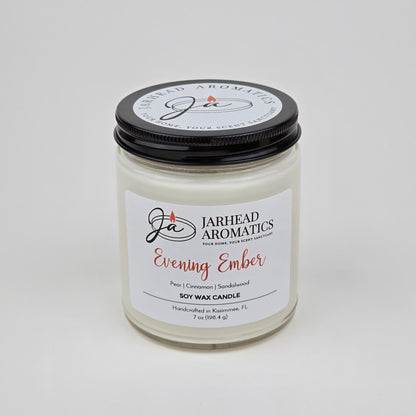 A white premium soy wax candle from Jarhead Aromatics, labeled Evening Ember Soy Wax Candle | Plum, Sandalwood & Smoke Candle, housed in a glass jar with a sleek black lid. This handcrafted candle is made in Kissimmee, FL and features notes of plum, sandalwood, and smoke.