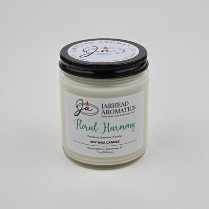 Experience the Floral Harmony Soy Wax Candle by Jarhead Aromatics—a hand-poured candle crafted in Kissimmee, FL. Presented in a clear jar with a black lid featuring the brand logo and text, this candle blends gardenia, jasmine, and tuberose for a long-lasting fragrance that infuses your space with delicate white floral notes.