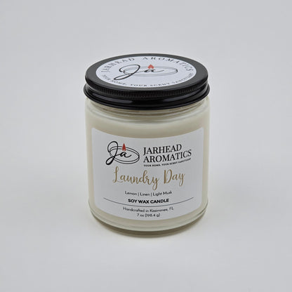 A 7 oz Jarhead Aromatics Laundry Day Soy Wax Candle, featuring fresh linen, lemon, and light musk scents. Handcrafted in Kissimmee, FL for a long-lasting aroma. The candle is displayed against a plain white background.
