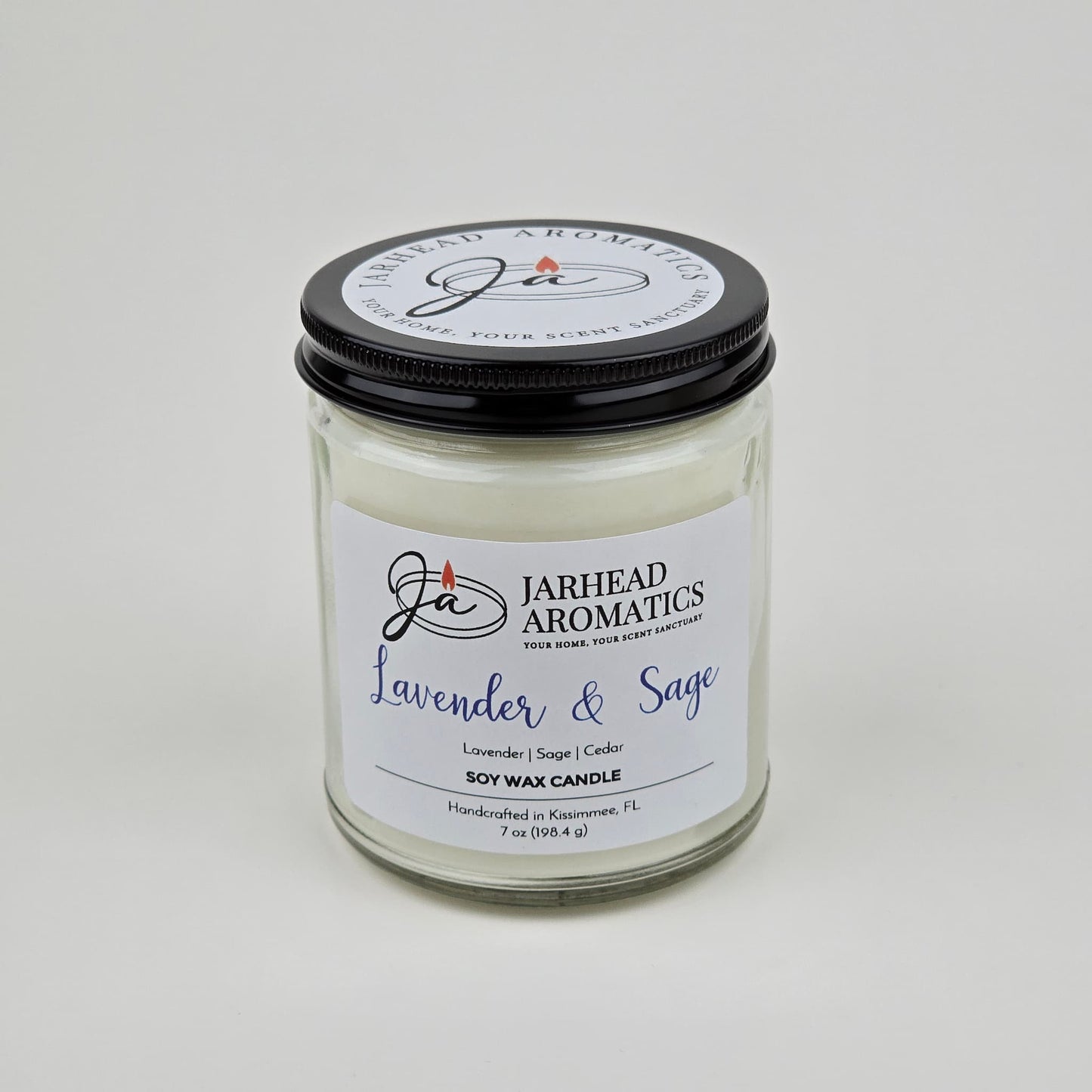 The Jarhead Aromatics Lavender & Sage Soy Wax Candle features calming lavender, sage, and sandalwood scents. Hand-poured in Kissimmee, FL, this glass jar candle with a black lid is perfect for adding relaxation to any space.