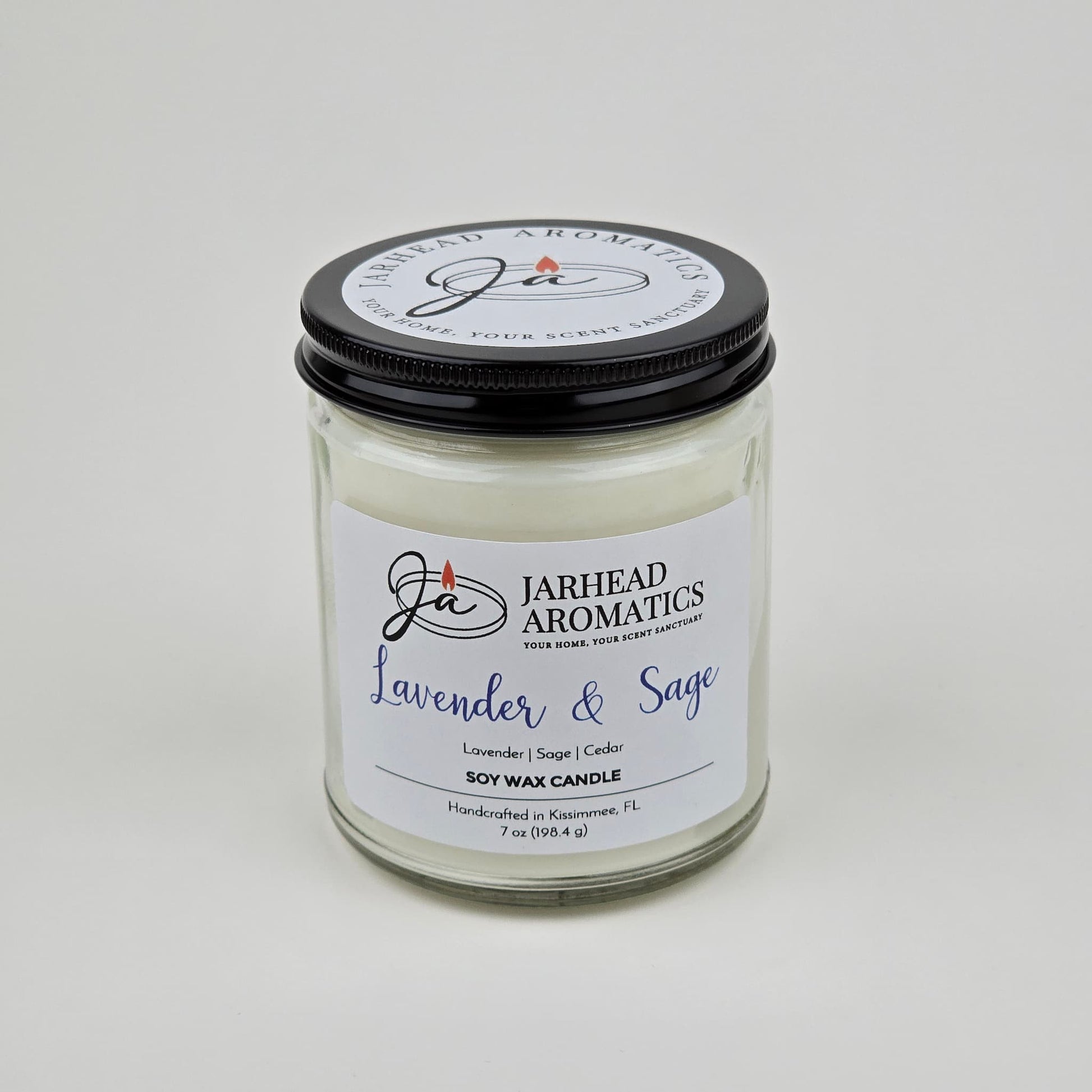 The Jarhead Aromatics Lavender & Sage Soy Wax Candle features calming lavender, sage, and sandalwood scents. Hand-poured in Kissimmee, FL, this glass jar candle with a black lid is perfect for adding relaxation to any space.