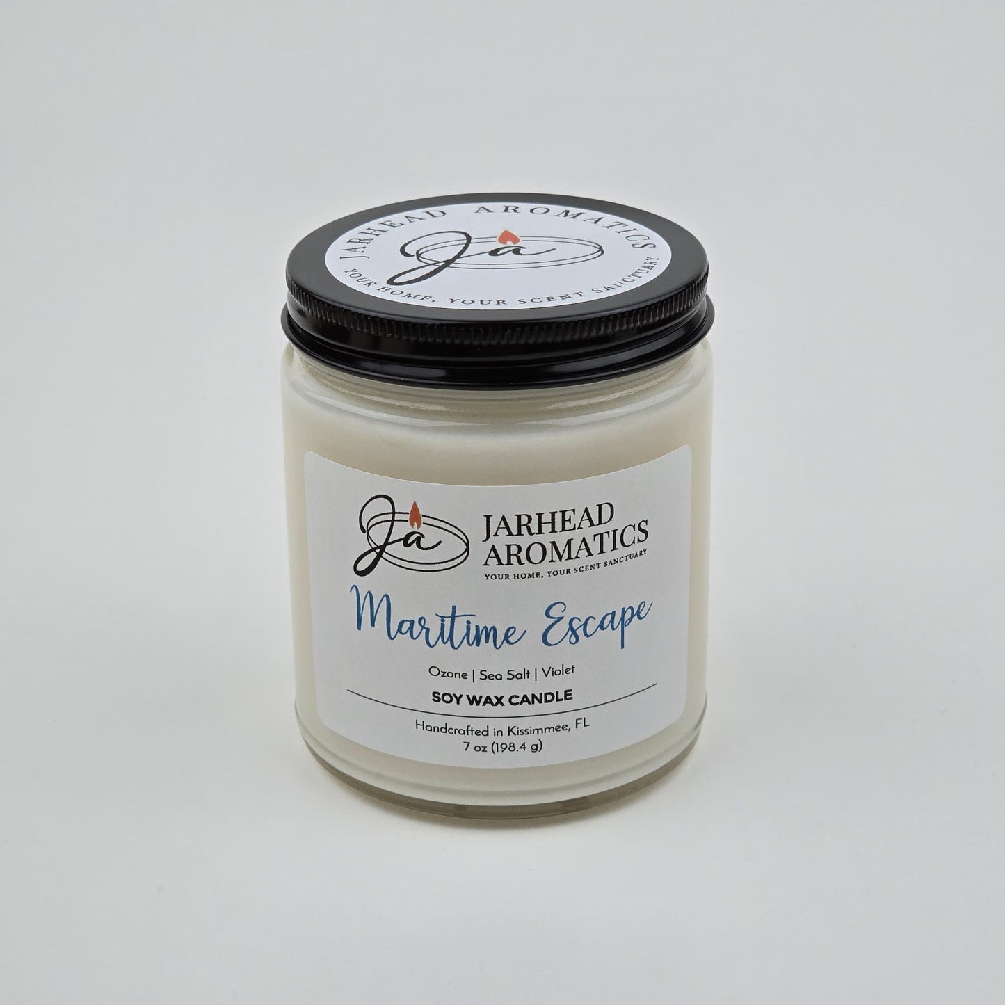 Introducing the Maritime Escape Soy Wax Candle by Jarhead Aromatics—a 7 oz white jar candle with a sleek black lid. Handcrafted in Kissimmee, FL, this coastal-inspired candle features notes of sea salt, ozone, and cedar for a fresh ocean fragrance. Its inviting scent brings refreshing seaside vibes to any space.