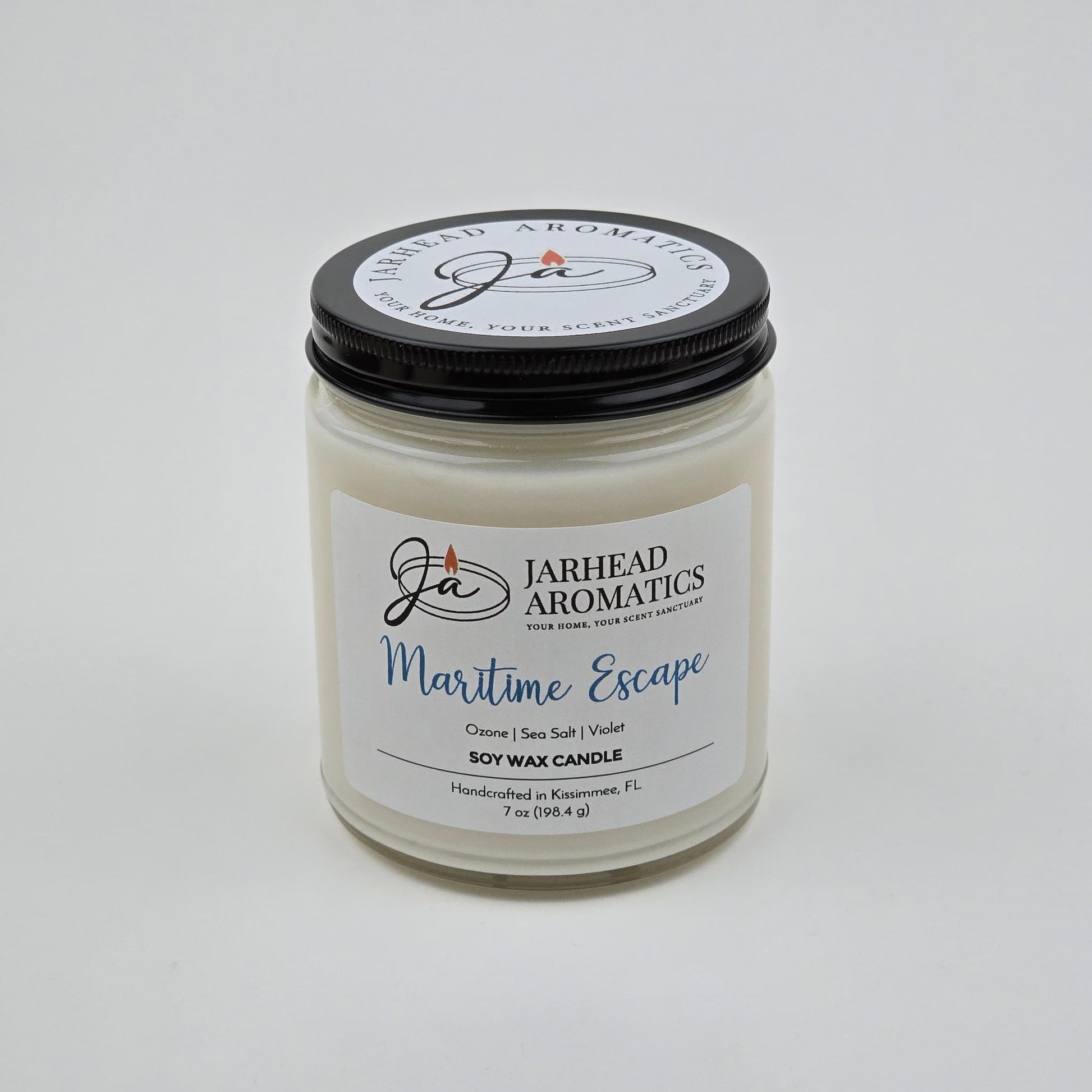 Introducing the Maritime Escape Soy Wax Candle by Jarhead Aromatics—a 7 oz white jar candle with a sleek black lid. Handcrafted in Kissimmee, FL, this coastal-inspired candle features notes of sea salt, ozone, and cedar for a fresh ocean fragrance. Its inviting scent brings refreshing seaside vibes to any space.