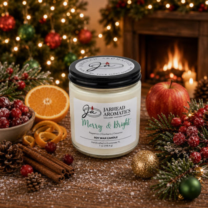 A Jarhead Aromatics Merry & Bright Soy Wax Candle | Citrus Cranberry, Warm Spice & Fir Holiday Candle sits on a festive table adorned with pinecones, apples, orange slices, cinnamon sticks, and holiday decorations. As the candle glows warmly, it fills the room with a cheerful winter fragrance while a twinkling tree and cozy fireplace shimmer in the background.
