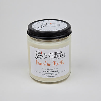 A white jar candle from Jarhead Aromatics, labeled Pumpkin Treats Soy Wax Candle, features a blend of pumpkin caramel, maple pecan, and vanilla fragrances. Handcrafted in Kissimmee, FL and weighing 7 oz, this autumn candle is made from soy wax—perfect for filling your home with a cozy fall scent.