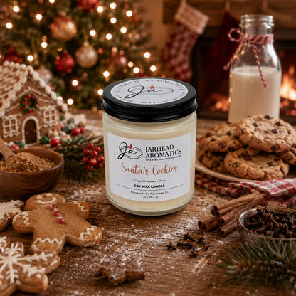A Jarhead Aromatics Santa’s Cookies Soy Wax Candle—featuring notes of ginger, brown sugar, molasses, and vanilla—rests on a wooden table beside gingerbread cookies, milk, and festive holiday decorations. In the cozy background, a Christmas tree and fireplace add to the seasonal atmosphere.