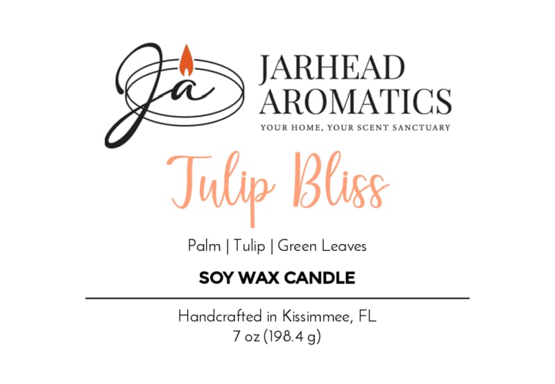 Jarhead Aromatics Tulip Bliss Soy Wax Candle | Peach, Tulip & Soft Musk. Handcrafted in Kissimmee, FL, this floral scented candle captures the essence of nature in every jar. 7 oz (198.4 g). Features a logo with a flame and initials JA.