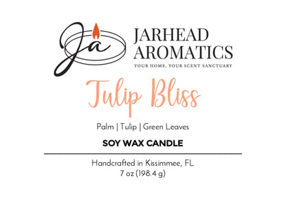 Jarhead Aromatics Tulip Bliss Soy Wax Candle | Peach, Tulip & Soft Musk. Handcrafted in Kissimmee, FL, this floral scented candle captures the essence of nature in every jar. 7 oz (198.4 g). Features a logo with a flame and initials JA.