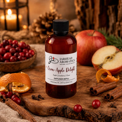 A bottle of Jarhead Aromatics Cran-Apple Delight Diffuser Refill | Cranberry, Apple & Warm Cinnamon rests on a wooden surface surrounded by cranberries, apples, orange peels, and festive autumn decor, filling your home with the perfect cozy seasonal fragrance.