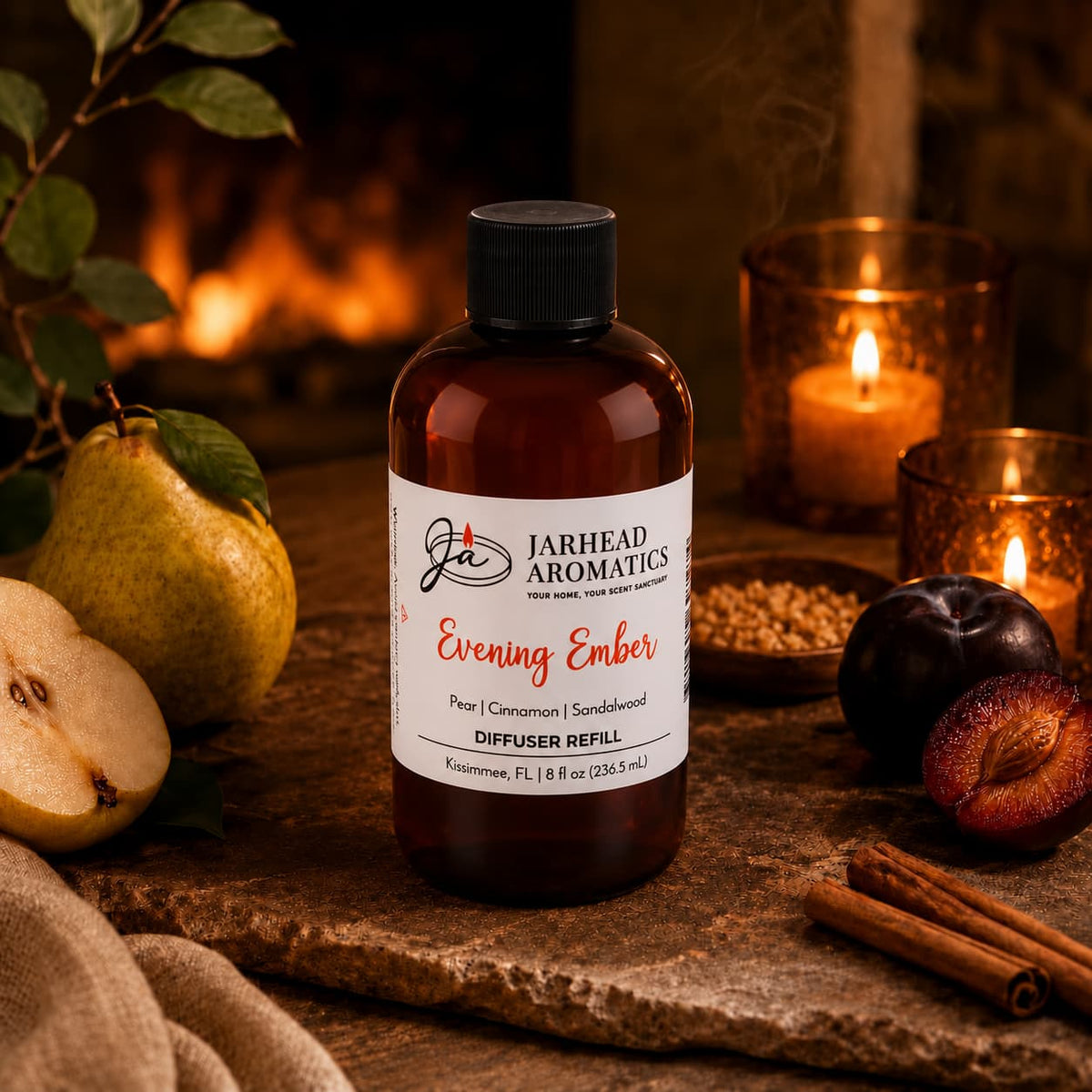 A bottle of Jarhead Aromatics Evening Ember Diffuser Refill | Plum, Sandalwood & Soft Smoke is set on a table alongside pears, plums, cinnamon sticks, and a glowing candle, all against a warm, rustic backdrop that creates a cozy and aromatic home fragrance ambiance.