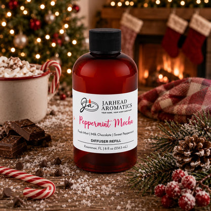 Amber bottle of Peppermint Mocha Diffuser Refill by Jarhead Aromatics on a wooden table, surrounded by chocolate, candy canes, and festive holiday decor.
