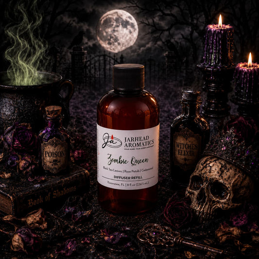 A shadowy, gothic tableau features a bottle of Jarhead Aromatics’ Zombie Queen Diffuser Refill—Black Tea, Rose Petals & Cedarwood—its singular home fragrance curling through the air. The scene is accented by flickering candles, mysterious potion bottles, a skull, dried roses, a haze-filled cauldron, and an open Book of Shadows set before the mist-shrouded gravestones of an ancient cemetery.