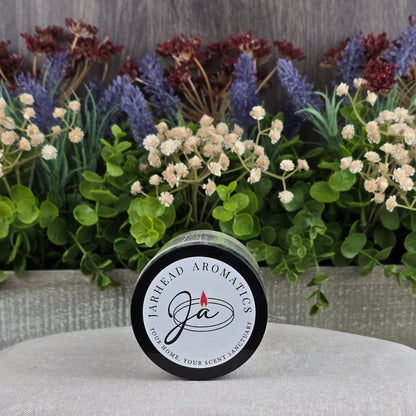 A Jarhead Aromatics Unscented Oats Milk Bath sits on a light surface in front of a planter with artificial green leaves, purple lavender, and white dried flowers—perfect for sensitive skin with its all-natural goat milk and buttermilk formula.