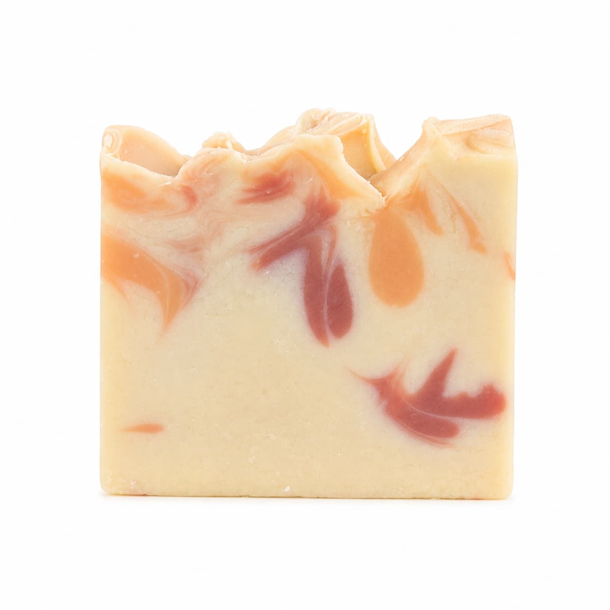 A rectangular bar of Jarhead Aromatics’ Apple + Spice Handmade Coconut Milk Artisan Soap, with a creamy base color accented by orange and reddish swirls and a textured, uneven top edge, displayed against a white background.