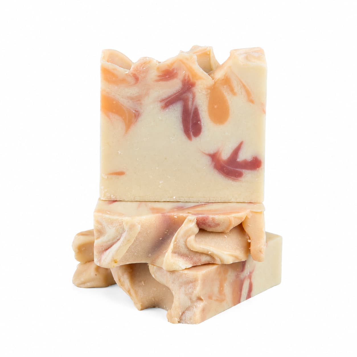 Two bars of Apple + Spice Handmade Coconut Milk Artisan Soap by Jarhead Aromatics, featuring a beige base with vibrant orange and red swirls, are stacked on a white background. The uneven edges highlight the artisanal craftsmanship, giving these soap bars a charmingly rustic look.
