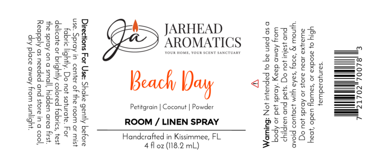 The Beach Day Room & Linen Spray by Jarhead Aromatics features usage directions, scent details (Coconut & Coastal Breeze), ingredients (Petitgrain, Coconut, Powder), warnings, and company info in black and orange on a white label.