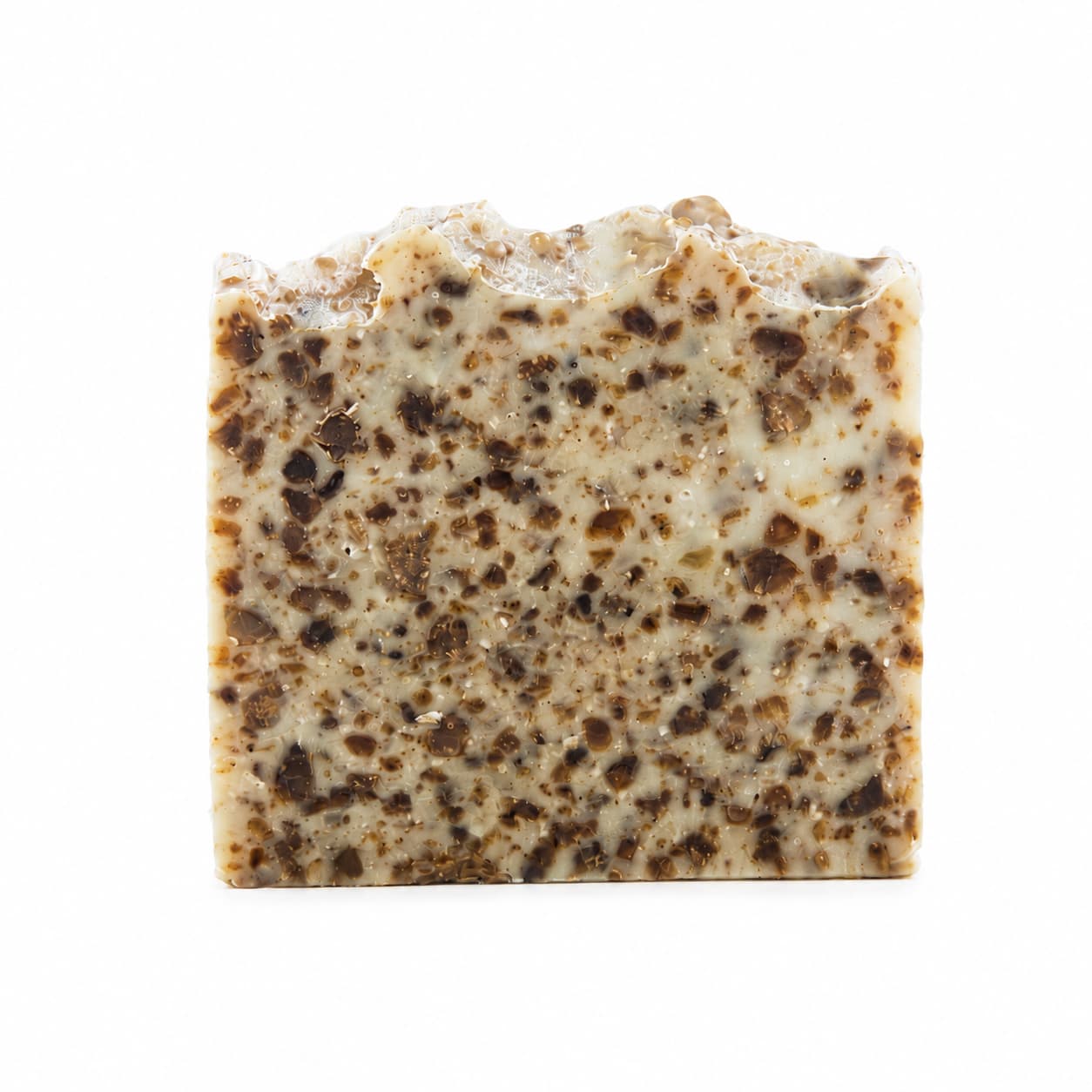 A rectangular bar of Jarhead Aromatics’ Black Soap + Lavender Handmade Natural Artisan Soap, featuring a rough, uneven top edge and a speckled brown and cream pattern throughout, stands upright against a white background.