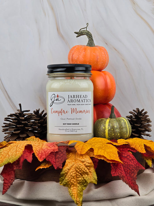 Jarhead Aromatics Campfire Memories - Soy Wax Candle rests before pumpkins, its campfire scent blending with autumn leaves and a green pumpkin on wood, stirring fond memories.