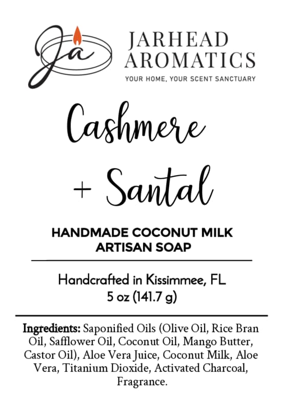 Jarhead Aromatics Cashmere + Santal Handmade Coconut Milk Artisan Soap | Warm Smoky Sandalwood Soap. Handcrafted in Kissimmee, FL with creamy coconut milk. Label displays full ingredients list and features a stylized candle flame logo. Experience the luxurious blend of cashmere and warm smoky sandalwood in every artisan bar.