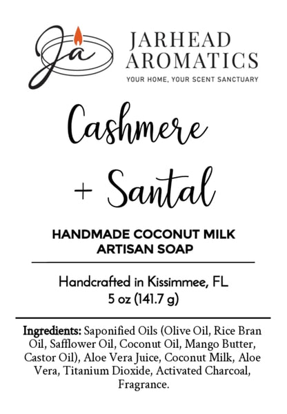 Jarhead Aromatics Cashmere + Santal Handmade Coconut Milk Artisan Soap | Warm Smoky Sandalwood Soap. Handcrafted in Kissimmee, FL with creamy coconut milk. Label displays full ingredients list and features a stylized candle flame logo. Experience the luxurious blend of cashmere and warm smoky sandalwood in every artisan bar.