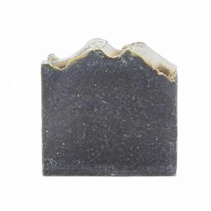 A bar of Jarhead Aromatics Charcoal + Tonka Handmade Artisan Soap, featuring warm tonka and activated charcoal, with an uneven, wavy top edge, displayed against a plain white background.