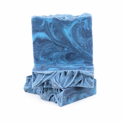 Two rectangular bars of Jarhead Aromatics’ Citron + Cedarwood Handmade Coconut Milk Artisan Soap, featuring blue marbled swirls and textured edges, stacked on a white background. These handcrafted soaps blend bright citrus and woodsy cedar fragrances with nourishing coconut milk for a luxurious bathing experience.