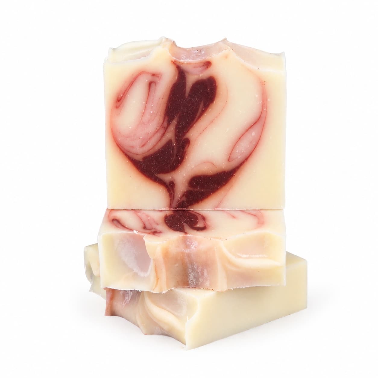 Three Citrus + Patchouli Handmade Natural Tallow Artisan Soap bars from Jarhead Aromatics are stacked, showcasing a creamy base with vibrant red swirled patterns. The top bar features a swirl reminiscent of a heart, emphasizing the artistry of this Bright Citrus & Earthy Patchouli soap. The background is plain white.