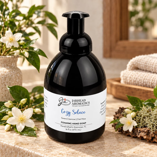 Black pump bottle of Cozy Solace Handmade Foaming Hand Soap on a vanity surrounded by jasmine flowers and oak moss.