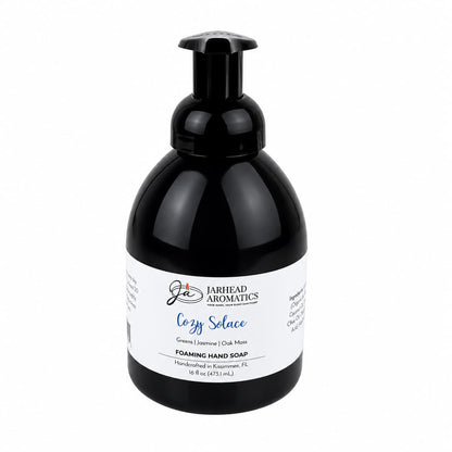 Black bottle of Jarhead Aromatics Cozy Solace Handmade Foaming Hand Soap with a pump dispenser and a white label reading Cozy Solace, Greens | Jasmine | Oak Moss.