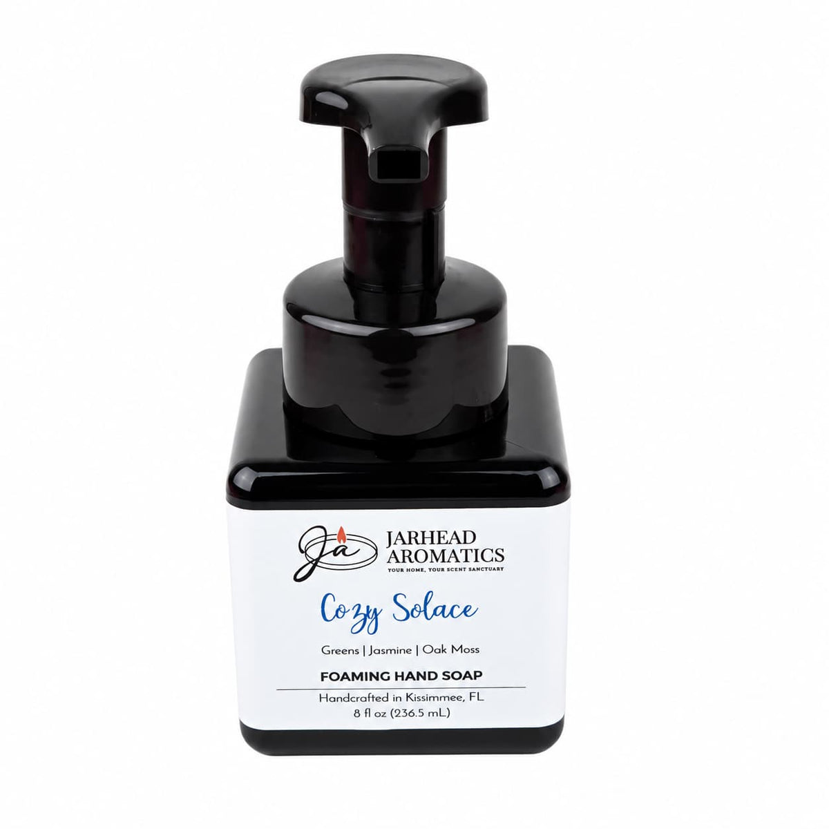 Square dark bottle of Cozy Solace Handmade Foaming Hand Soap with a black pump dispenser and a label reading Greens | Jasmine | Oak Moss.