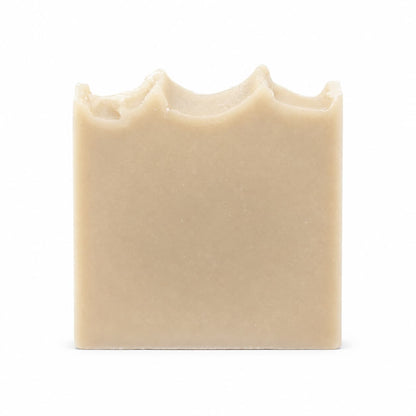 A beige rectangular bar of Jarhead Aromatics Eucalyptus + Mint Handmade Natural Goat Milk Artisan Soap, featuring an uneven, wavy top edge, is set against a plain white background.