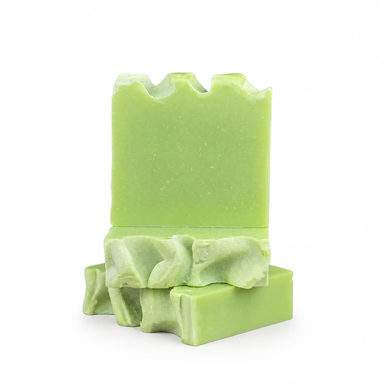 Three rectangular green bars of Jarhead Aromatics’ Eucalyptus + Spearmint Handmade Coconut Milk Artisan Soap are stacked on a white background. The top bar features a jagged edge, the middle has a wavy edge, and the bottom is mostly flat. These cooling mint and eucalyptus spa soaps have a smooth, handmade appearance.