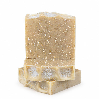 Two natural, handmade soap bars from Jarhead Aromatics in a soothing beige hue with a textured surface and gold flecks—one bar stands upright while the other two are stacked horizontally against a white background. Perfectly crafted, these Fragrance-Free Oatmeal Handmade Natural Goat Milk Artisan Soaps are unscented and made with care using goat milk and oatmeal.