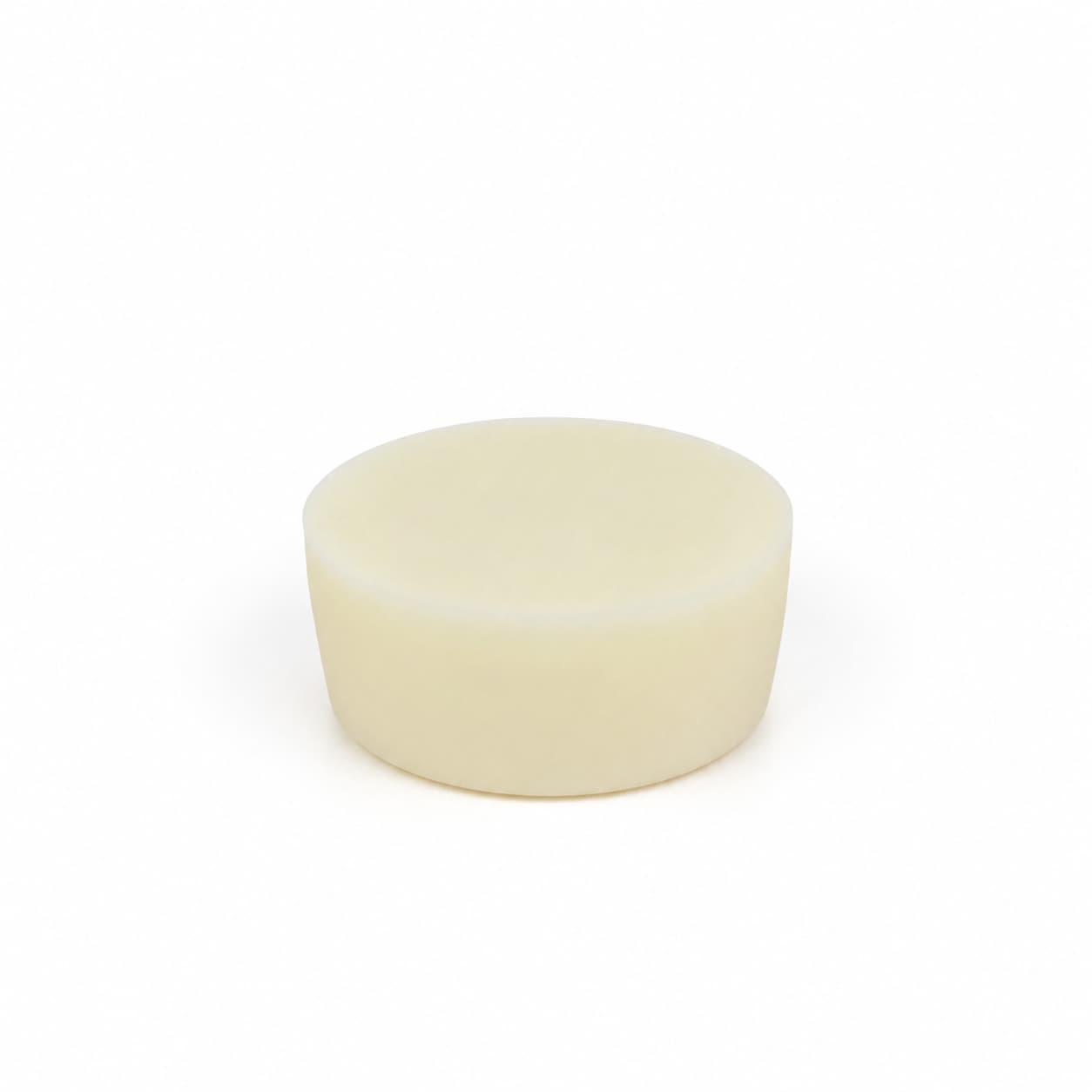A plain, round, off-white solid object with smooth sides and top, resembling a bar of soap, sits centered on a white background—this is the Lemon Handmade Natural Solid Dish Soap by Jarhead Aromatics, an elegant and eco-friendly citrus kitchen cleaning bar infused with lemon essential oil.