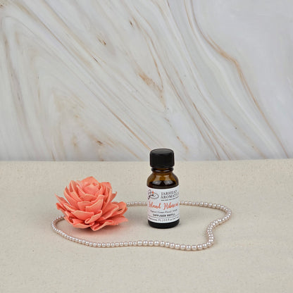 A Jarhead Aromatics Island Hibiscus Cold Air Diffuser Refill with tropical floral & melon notes, a pink artificial flower, and a string of pearls are displayed on a light surface before a marble-patterned background.