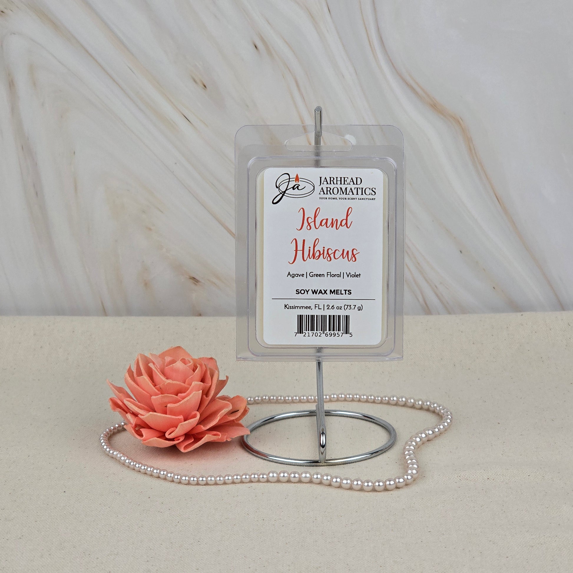 Jarhead Aromatics Island Hibiscus Soy Wax Melt | Tropical Floral & Melon Wax Melts is shown on a metal stand with a peach artificial flower and pearl necklace, highlighting its long-lasting, tropical floral-melon fragrance.