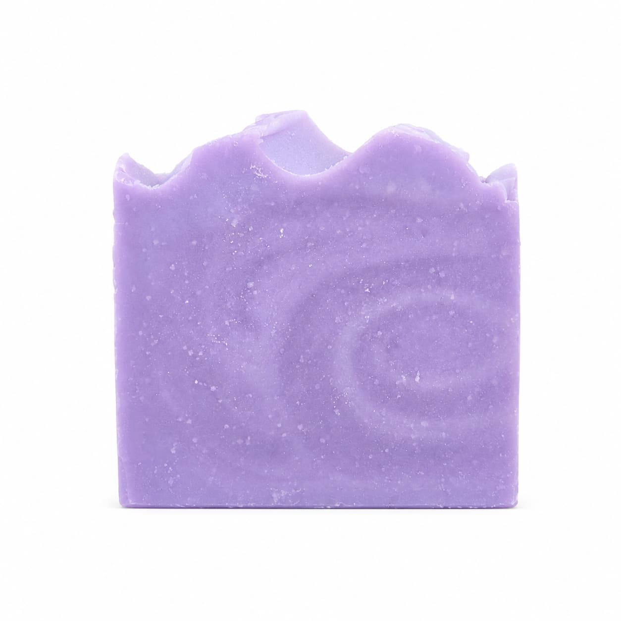 A rectangular bar of Jarhead Aromatics Lavender + Chamomile Handmade Coconut Milk Artisan Soap, featuring a calming lavender hue, wavy top edge, and delicate swirl patterns, is displayed against a plain white background.