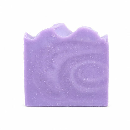 A rectangular bar of Jarhead Aromatics Lavender + Chamomile Handmade Coconut Milk Artisan Soap, featuring a calming lavender hue, wavy top edge, and delicate swirl patterns, is displayed against a plain white background.