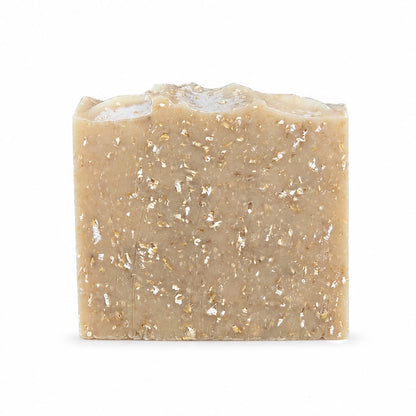 A rectangular bar of Jarhead Aromatics’ Lavender + Oatmeal Handmade Natural Goat Milk Artisan Soap, featuring a natural beige hue with visible flecks and an uneven top edge, stands upright on a plain white background.