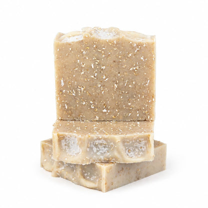 Three beige bars of Lavender + Oatmeal Handmade Natural Goat Milk Artisan Soap by Jarhead Aromatics, featuring visible flecks and rustic, uneven edges, are stacked against a white background.