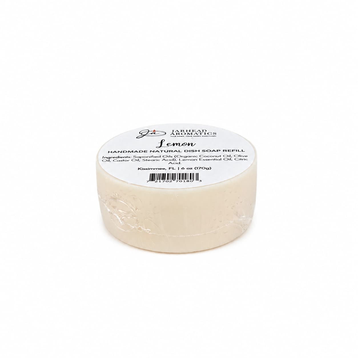 A round bar of Jarhead Aromatics Lemon Handmade Natural Solid Dish Soap, labeled with product details and information about its plant-based ingredients in off-white packaging, is displayed on a plain white background.