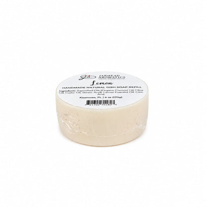 A round bar of Jarhead Aromatics Lemon Handmade Natural Solid Dish Soap, labeled with product details and information about its plant-based ingredients in off-white packaging, is displayed on a plain white background.
